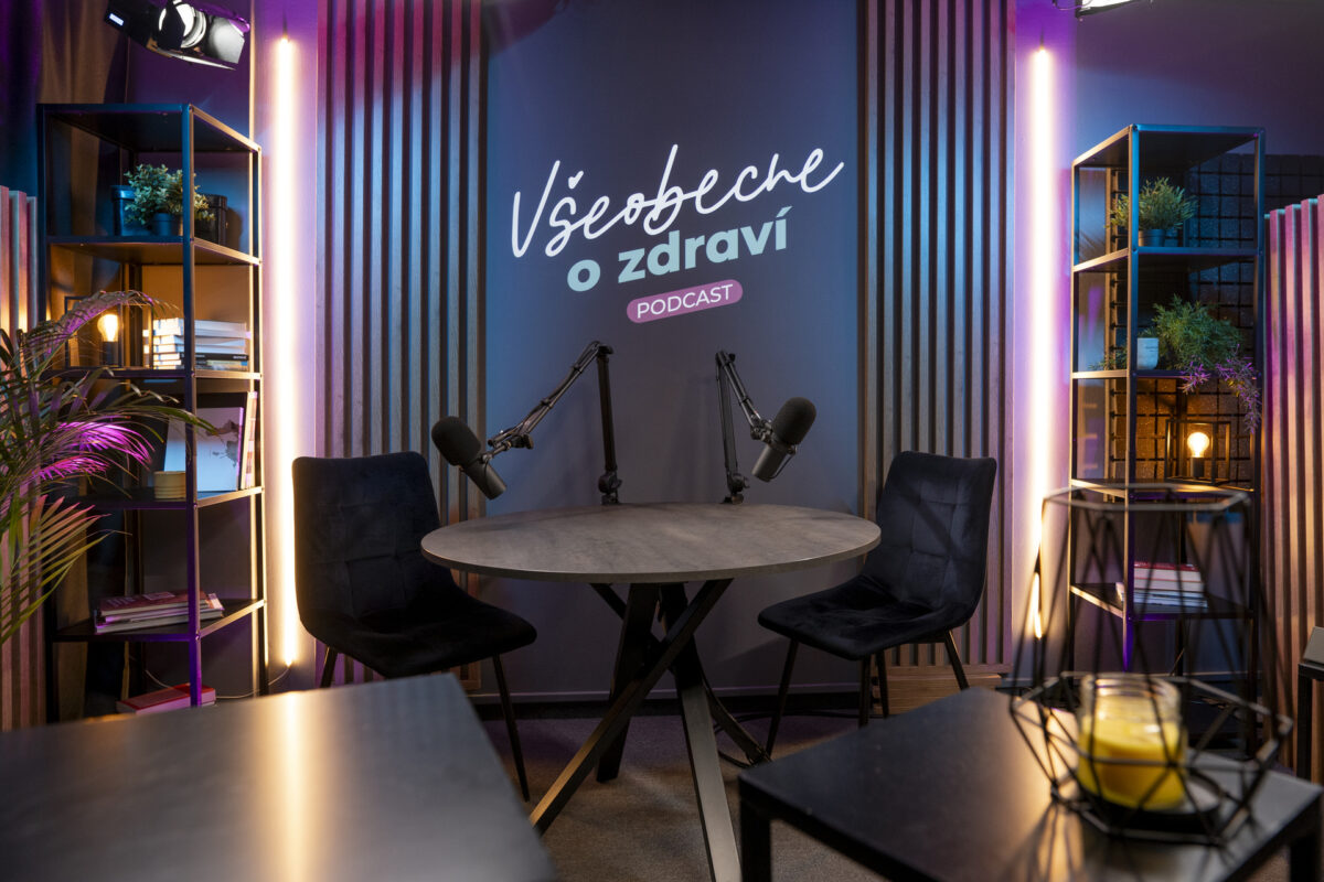 Moderné variabilné podcastové štúdio s dvoma mikrofónmi, stolom, stoličkami a svetelným logom. Podcastové štúdio Bratislava – profesionálne nahrávanie.