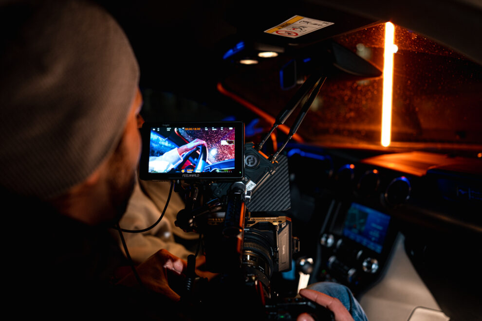 Kameraman pri nakrúcani reklamného spotu zaznamenáva detailný záber v interiéry auta, making of fotografia z nakrúcania reklamného videa, Produkčný tím Shape Production, detailný záber kamery z nakrúcania reklamného spotu, ako vyzerá práca kameramana v Shape Production